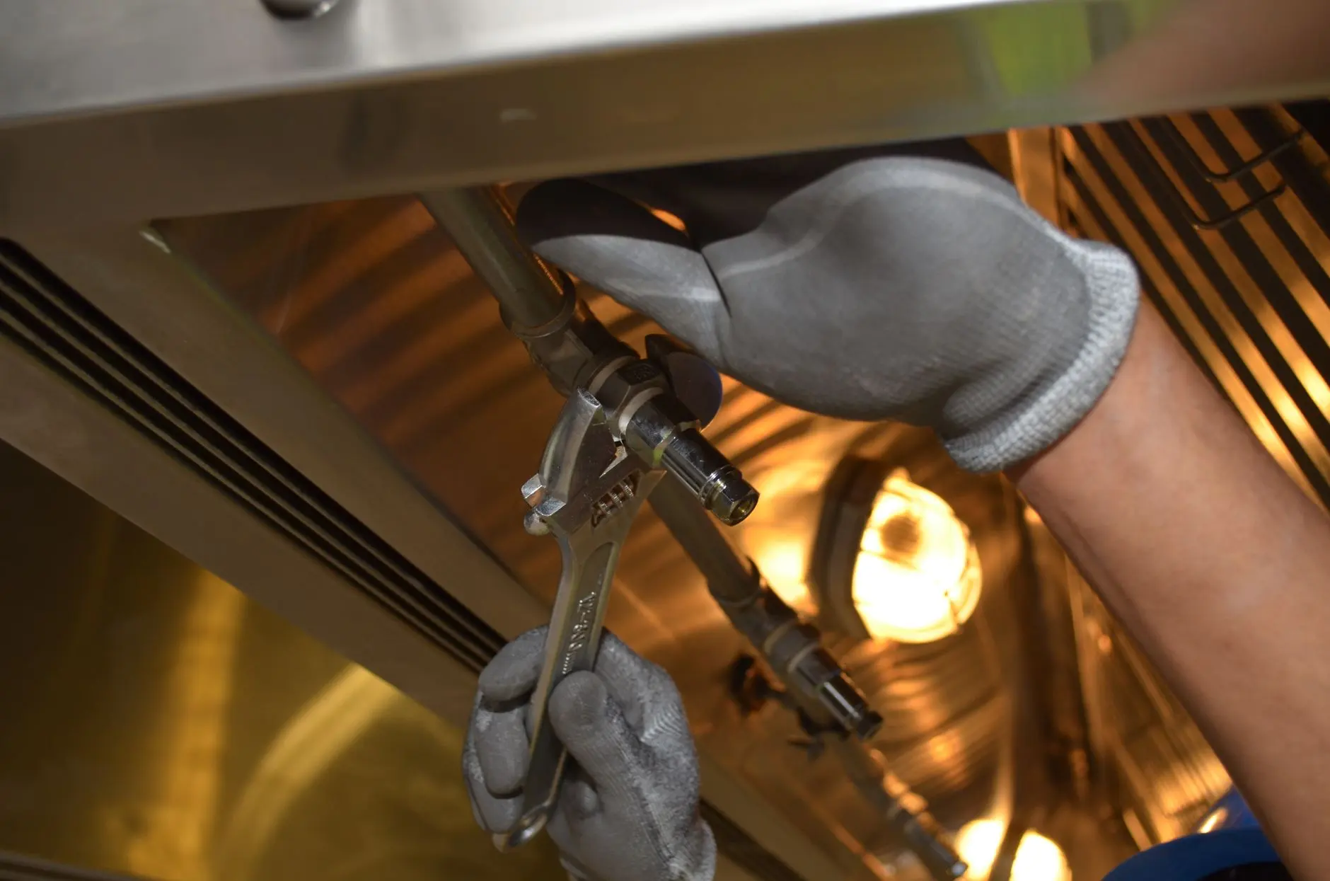 Licensed plumber repairing a supply line under a kitchen sink
